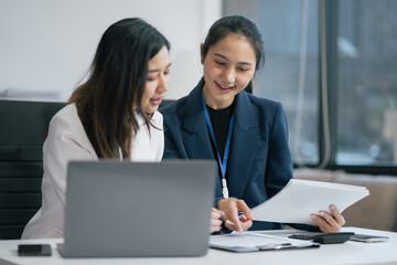 Business, technology and office concept - two businessmen with laptop, tablet pc computer and papers having discussion in modern office.