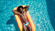 © Pixel_Studio_8 - Happy gay afro black man in the pool sunbathing on top of a float wearing a rainbow LGBT swimsuit. Black man in hotel pool with big smile having fun on summer vacation