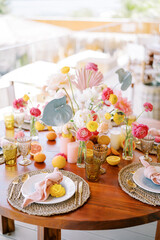 Wall Mural - Plates with knotted napkins on mats stand on a festive table with colorful flowers