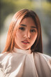 © chokniti - A woman with long brown hair is wearing a white shirt and a white scarf