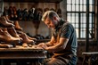 male craftsman shoemaker working on his carving with his hands surrounded by leather and shoes