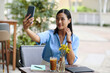Smiling Vietnamese businesswoman taking selfie at outdoor cafe table