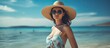 An elegant lady wearing a stylish hat and trendy sunglasses enjoys the sunny day by the sea shore