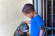 african boy playing with his boerboel puppy dog in front of the house, in the township, in the morning