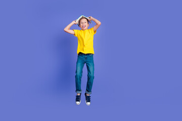 Wall Mural - Photo of funky cheerful crazy nice boy wear stylish yellow clothes jump up have fun book on head isolated violet color background