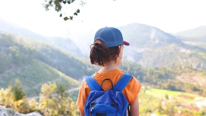 Wall Mural - Adventures and travel. a child with a backpack stands on a mountain path and looks at the mountains. hiking and active healthy lifestyle. traveling with children.