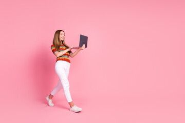 Wall Mural - Full size profile photo of nice cheerful girl walking hold use laptop empty space isolated on pink color background