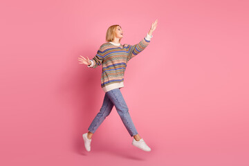 Sticker - Full size photo of impressed woman wear ornament pullover jumping look at promo empty space waving palm isolated on pink color background