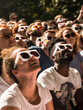 Group of people watching a solar eclipse with protective glasses