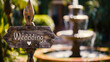 A wooden 'Wedding' sign with a heart on it in a sunny garden setting