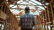 © lelechka - Back view of man on helmet at wooden house framework