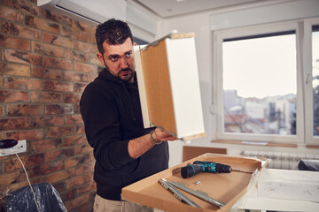 Wall Mural - Man working and assembling furniture in a new apartment.