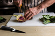 Cook slicing an artichoke on a cutting board