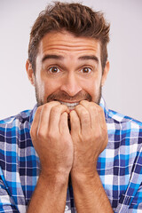 Wall Mural - Nervous, portrait and man with nail bite for anxiety, fear and funny stress gesture in a studio. Worried, scared and male person with hands to face for comedy with grey background and modern style