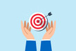 Businessman hand holds bullseye with arrow, illustrating aiming business target accurately. Concept of setting goals, focus and concentration to achieve success, pursuing objectives with purpose