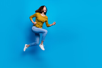 Wall Mural - Full length photo of excited sweet woman wear shirt hurrying jumping high empty space isolated blue color background
