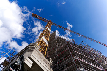 Looking up yellow crane at construction site of apartment building at Swiss City of Zürich on a blue cloudy spring day. Photo taken March 21st, 2024, Zurich, Switzerland.