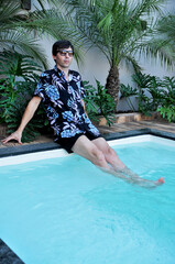 Wall Mural - homem relaxando em piscina com paisagismo tropical no verão 