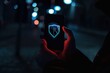 © Igor - shield symbol glowing on a smartphone in hand dark technology background