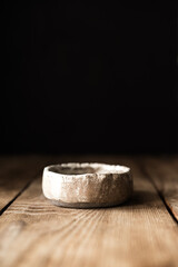 An empty antique clay bowl on an old wooden table on a black background. Japanese style. Wabi-sabi. Layout. Place for the text at the top.