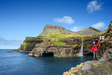 Fototapeta Konie - Tourist Near Mulafossur Waterfall in Gasadalur, Faroe Islands