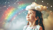 © sattawat - A young girl has fun playing in her thoughts dreams and creativity ,girl with cloud and rainbow pop up above her head .