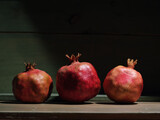 Fototapeta  - Red organic grown pomegranates in bright sunlight with copyspace. Natural fruit concept image.