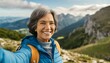 Cheerful senior woman taking selfie shot while hiking in the mountains