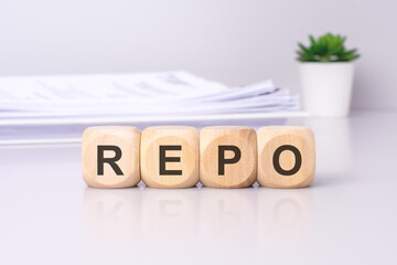 Wall Mural - The wooden cubes displaying the text 'REPO' against a light gray background signify a focus on the repurchase agreements or repos in financial markets.