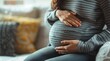 Close up of a pregnant woman holding her belly at home, close up shot, blurred background with copy space. Pregnancy background
