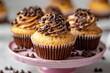 © Georgii - Gourmet chocolate chip cupcakes on a pink stand, perfect for dessert menus