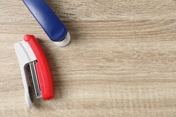 Wall Mural - Color staplers on wooden table, flat lay. Space for text