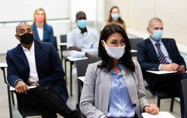 Wall Mural - Portrait of focused asian businesswoman wearing protective mask participating in corporate seminar in conference room. Concept of prevention measures to reduce infection risk in pandemic..