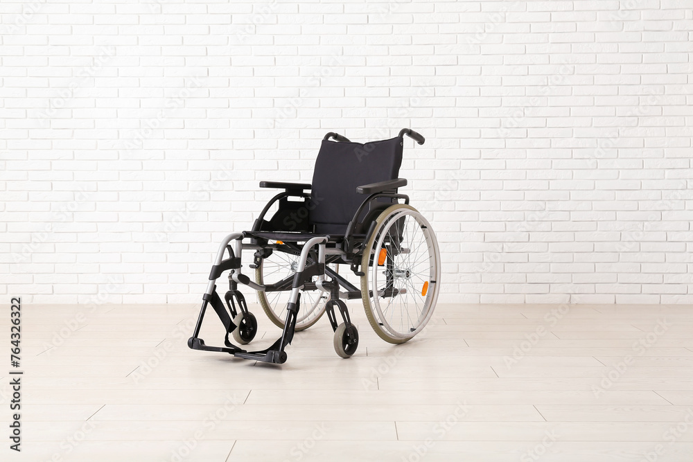 Empty wheelchair near white brick wall