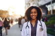 Young black female doctor wearing a white coat and stethoscope, blurred background