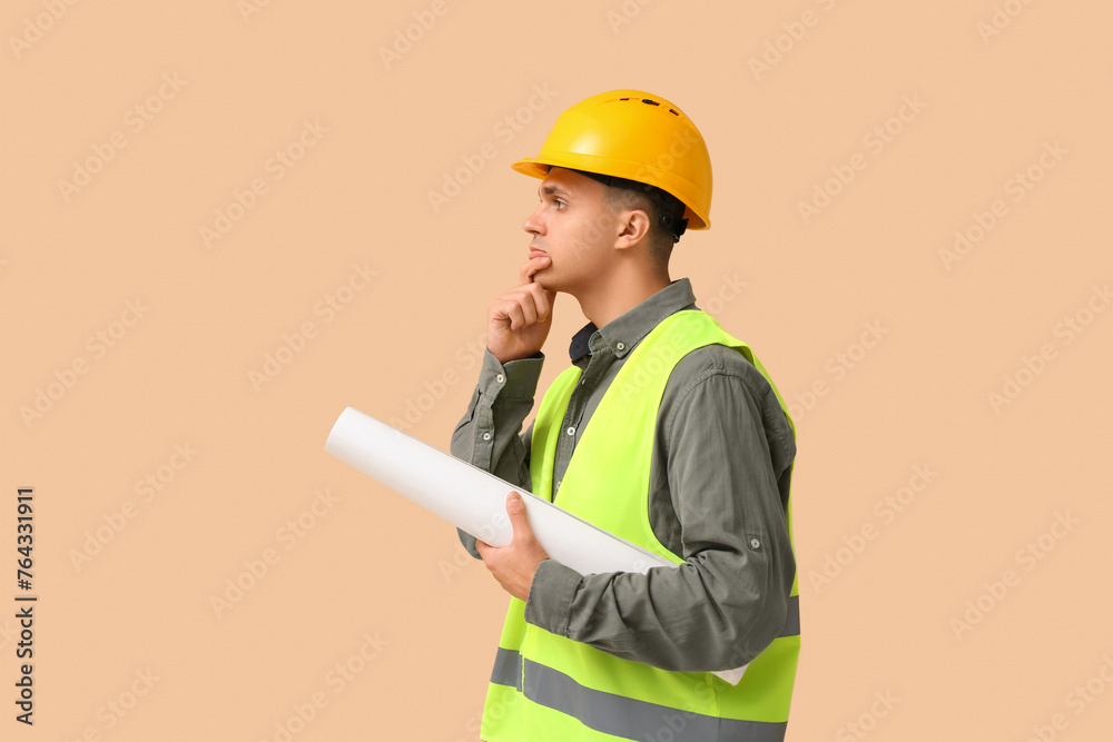 Young male engineer with blueprint on beige background
