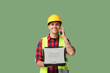 © Pixel-Shot - Young male engineer with laptop talking by phone on green background