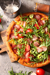 Wall Mural - Wooden board of delicious pizza with tomatoes and arugula on grey background