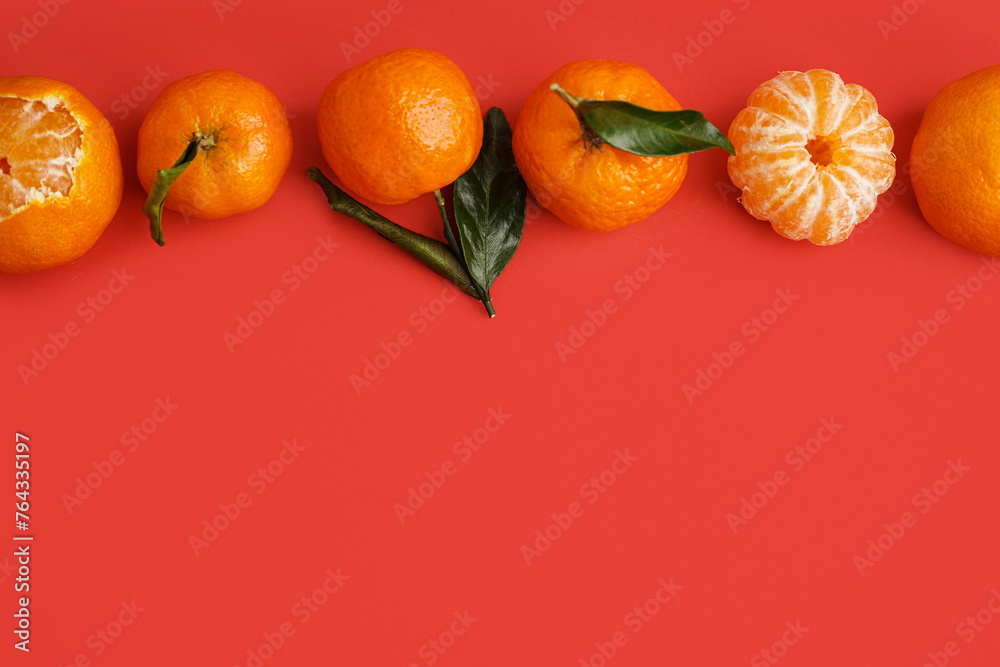 Tasty tangerines and leaves on red background