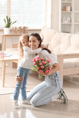 Wall Mural - Little girl congratulating her mom with bouquet of flowers and hugging at home. Mother's Day celebration