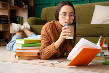 Wall Mural - Young woman with book drinking coffee on floor at home