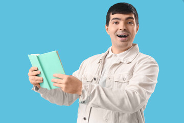 Wall Mural - Happy young man reading book on blue background