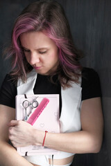 Portrait of a female hairdresser with professional scissors and pink comb in barber shop