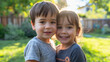 Young toddler preschool brother and sister standing together outdoors in sunny grass backyard in summer, smiling at camera. Little boy and girl, children family love, two siblings bonding hugged