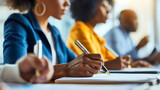 Fototapeta  - Closeup of African American businesswoman holding the pen and signing the contract, sitting with coworkers and colleagues in office, job meeting discussion, workplace brainstorming