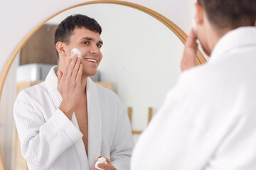 Sticker - Young man applying cleansing foam near mirror in bathroom