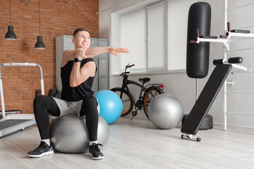 Wall Mural - Sporty young man training on fitball at gym