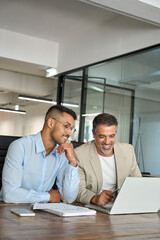 Wall Mural - Two busy happy business men partners working together talking using laptop in office. Male manager and employee looking at computer discussing investment business project at office meeting. Vertical