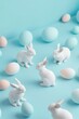 Easter pattern made of cute white bunnies and eggs on a blue pastel background. Abstract minimal Easter concept.	