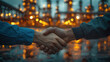 © bird_saranyoo - Two businessmen shake hands with an oil refinery in the background
